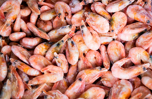 Close-up of a pile of frozen pink shrimps. Natural pink seafood background.