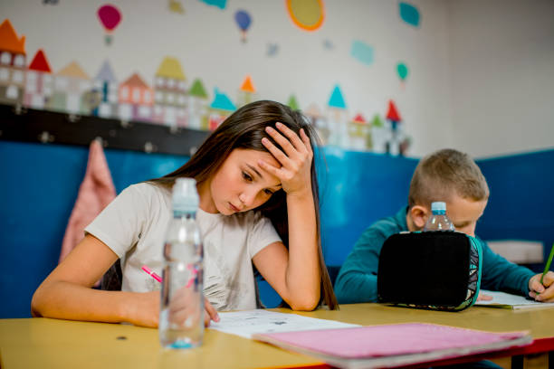 istock Elementary schoolchildren writing at the desk in the classroom. 1279847682