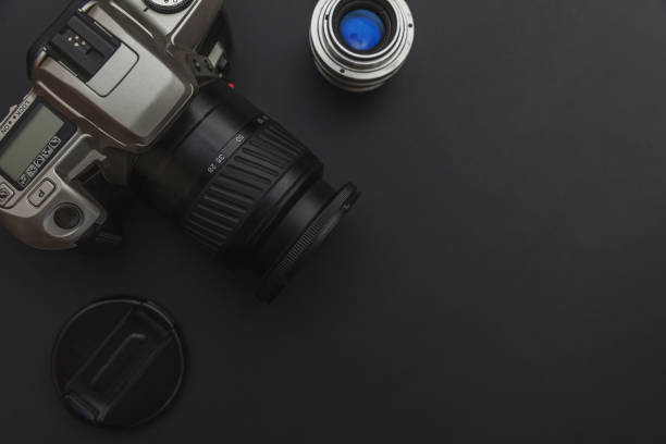 istock Photographer workplace with dslr camera system and lens on dark black table background. Hobby travel photography concept. Flat lay top view copy space 1279848280