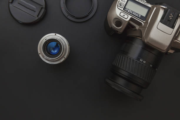 istock Photographer workplace with dslr camera system and lens on dark black table background. Hobby travel photography concept. Flat lay top view copy space 1279848300