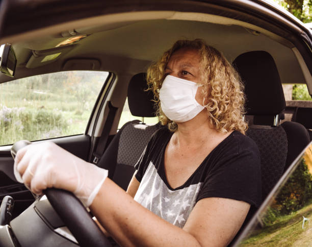 femme conduisant avec la voiture avec le masque de visage - science and technology science healthcare and medicine showroom photos et images de collection