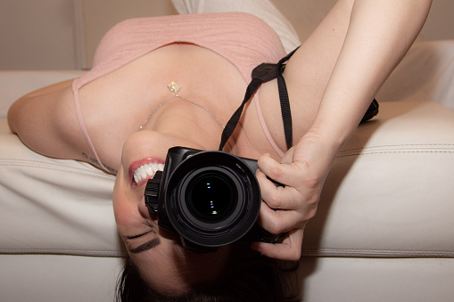 woman lying in bed holding photo camera