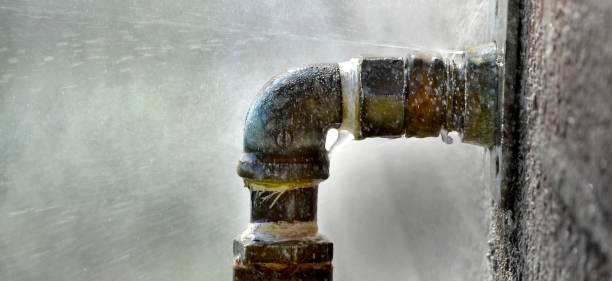 istock Old rusty pipe with leak and water spraying out 1279853702