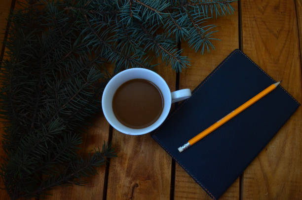 istock A cup with coffee, a black notebook for notes, a Christmas tree and a pencil. Office set, cases, plans. 1279855446