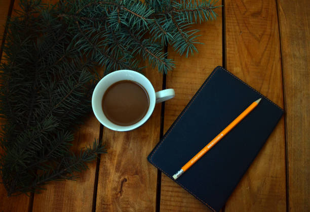 istock A cup with coffee, a black notebook for notes, a Christmas tree and a pencil. Office set, cases, plans. 1279855450