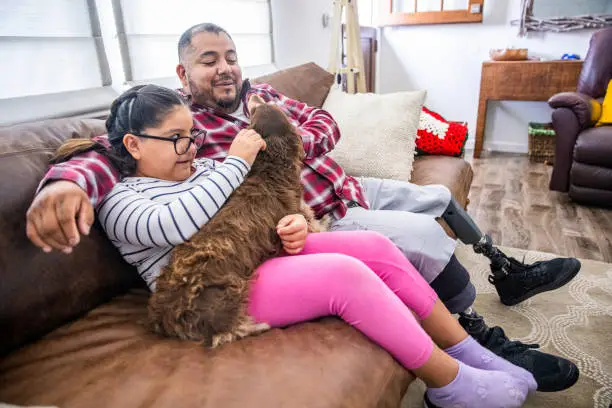 Photo of Disabled Father and Daughter playing with Long Haired Dachshund Dog