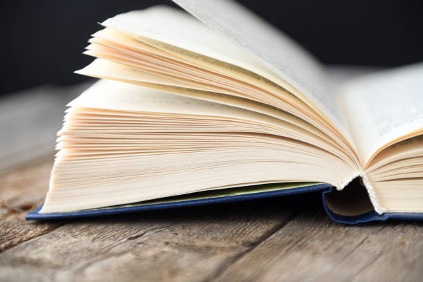 istock Open book on an old wooden table with a black background. 1279856647