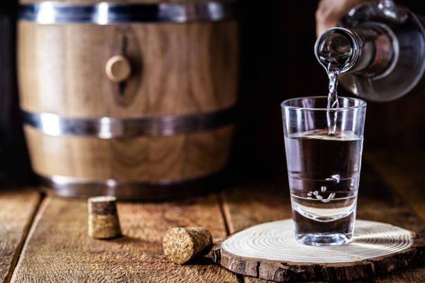 verre de boisson alcoolisée avec bouteille, verre de remplissage à la main. image de bar, carlin, spiritueux du type aguardente, comme la tequila, le rhum, la vodka ou la cachaça - whisky cocktail glass rum photos et images de collection