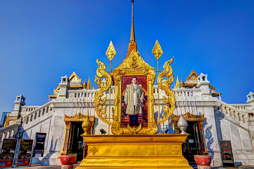 Bangkok, Thailand - December 25, 2019: A portrait of the King of Thailand outside of the temple gold buddha and exterior details of the Wat Traimit temple in Bangkok