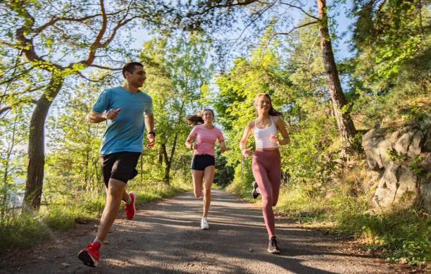 three young people jogging together in nature. - nordic running imagens e fotografias de stock