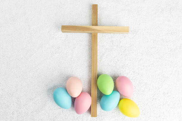 les oeufs colorés de pâques et une croix en bois montrent le côté religieux et laïque de pâques sur un fond blanc de tissu de terry - easter egg religion cross spirituality photos et images de collection