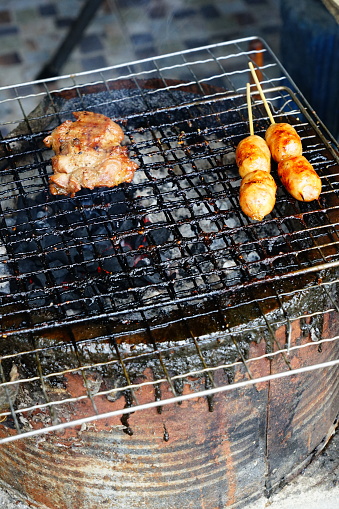 Isaan sausage being grilled on the traditional stove with Thai street food