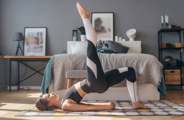 fitness-frau trainieren zu hause und tun einbeinige glute brücke - bridge exercise stock-fotos und bilder