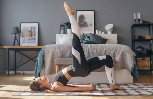 Fitness woman working out at home and doing single-leg glute bridge Fitness woman working out at home and doing single-leg glute bridge. woman lying on the floor isolated stock pictures, royalty-free photos & images