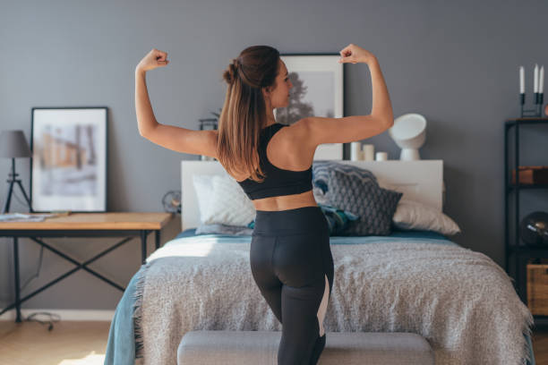 retrato de jovem mulher fitness mostrando músculos. vista para trás. - muscular build - fotografias e filmes do acervo
