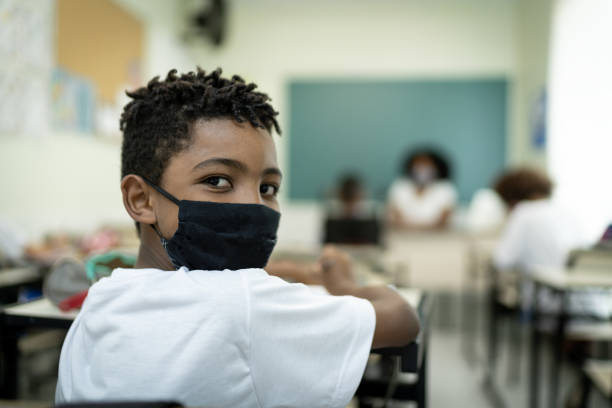 Portrait wearing face mask of a schoolboy studying in the classroom Portrait wearing face mask of a schoolboy studying in the classroom reopening photos stock pictures, royalty-free photos & images