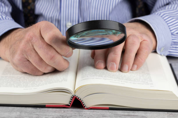 istock close up view of an elderly man using a magnifying glass to read a book 1279865181
