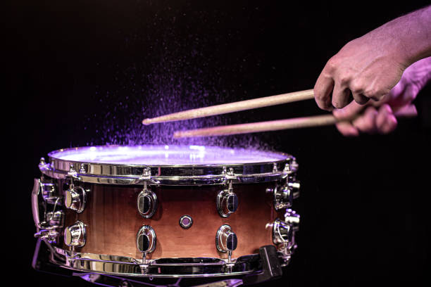 istock Drum sticks hitting snare drum with splashing water on black background under studio lighting. 1279865554