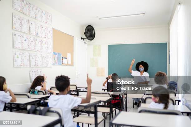 Teacher Teaching In Classroom Respecting Social Distancing Between Students Stock Photo - Download Image Now