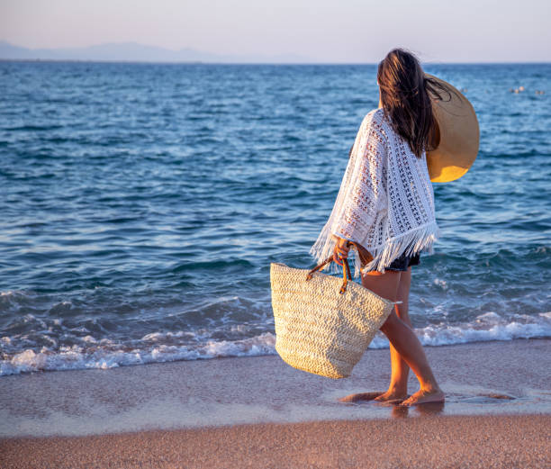 istock Beautiful boho model in a hat with a wicker bag on the beach 1279867638