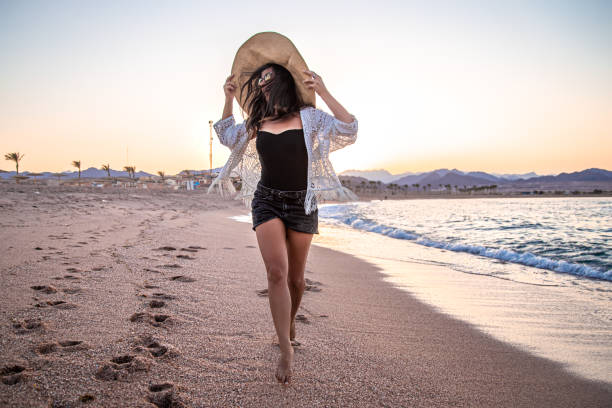 istock Woman at sunset on the beach in a hat. 1279867639