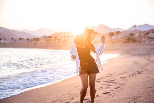 istock Woman at sunset on the beach in a hat. 1279867645
