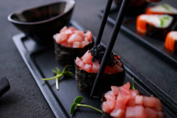 chopsticks taking gunkan maki sushi from plate - susi imagens e fotografias de stock