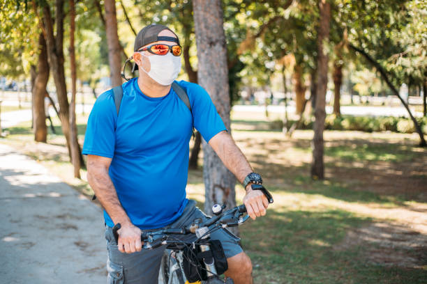istock Man wearing face mask standing on a park with bicycle 1279874158