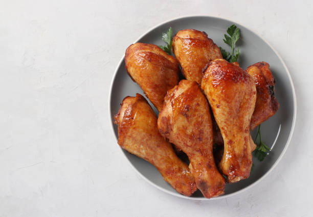 Roasted chicken drumsticks in honey and soy sauce on grey plate, top view, with space for text stock photo