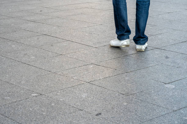 istock Sidewalk. Walking man legs wearing white shoes and jeans, motion blur. Selective focus, copy space for text. 1279877089