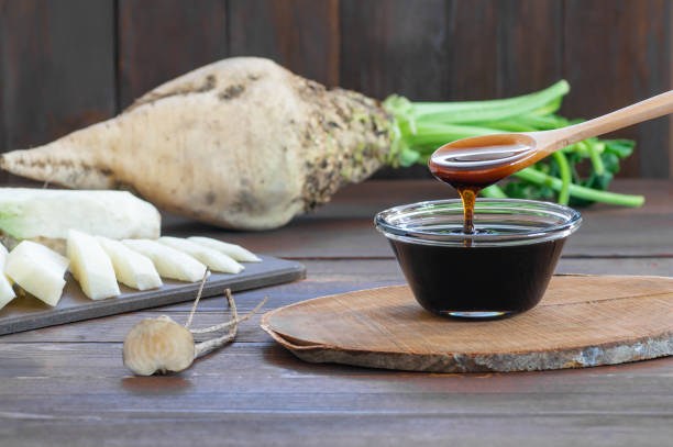 zuckerrübenmelasse in glasschüssel mit frischer zuckerrübenpflanze, gesunde nahrung, beta vulgaris - molasses stock-fotos und bilder