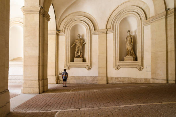 молодой мальчик, глядя на статую на внешней площади входа в палаццо барберини в риме, италия - palazzo barberini стоковые фото и изображения