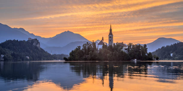 istock Lake bled with church under orange sky 1279879359