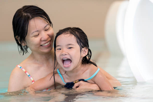 Happy mother and baby daughter at swimming pool Happy mother and baby daughter at indoor swimming pool kid and parent at pool stock pictures, royalty-free photos & images