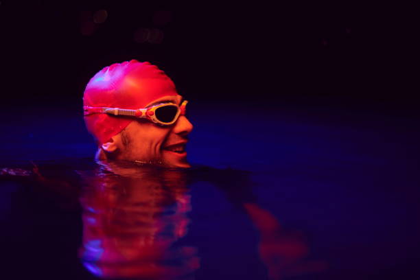 authentic triathlete swimmer having a break during hard training on night neon gel light