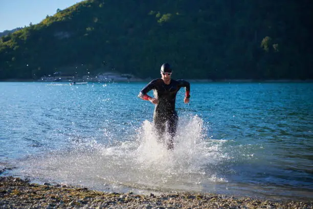 triathlon athlete start swimming training splashing water while running and jumping
