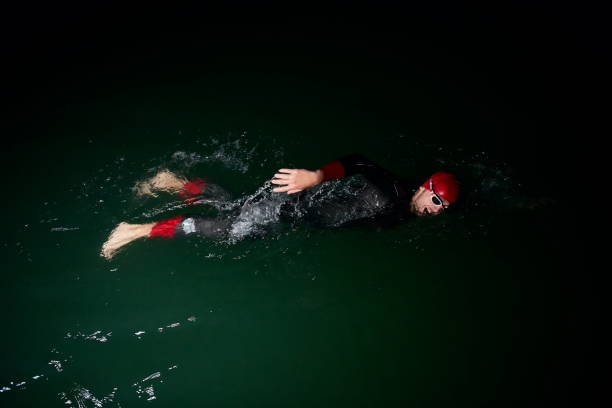 istock triathlon athlete swimming in dark night  wearing wetsuit 1279888821