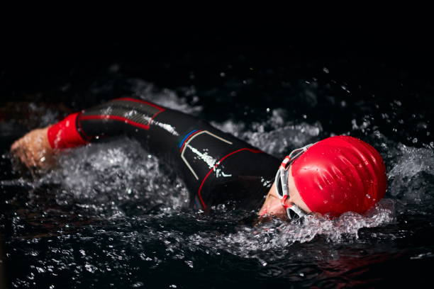istock triathlon athlete swimming in dark night  wearing wetsuit 1279888832