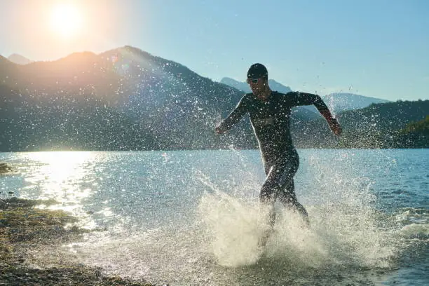 triathlon athlete start swimming training splashing water while running and jumping