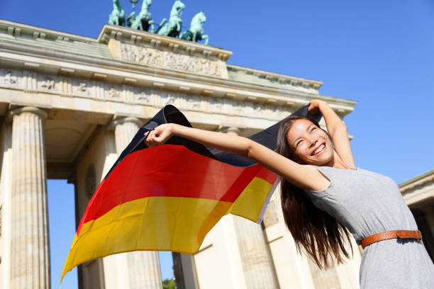 deutsche flagge frau glücklich am berliner brandenburger tor - tag der deutschen einheit stock-fotos und bilder