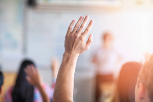 istock Teenage students with raised hand in classroom 1279895859