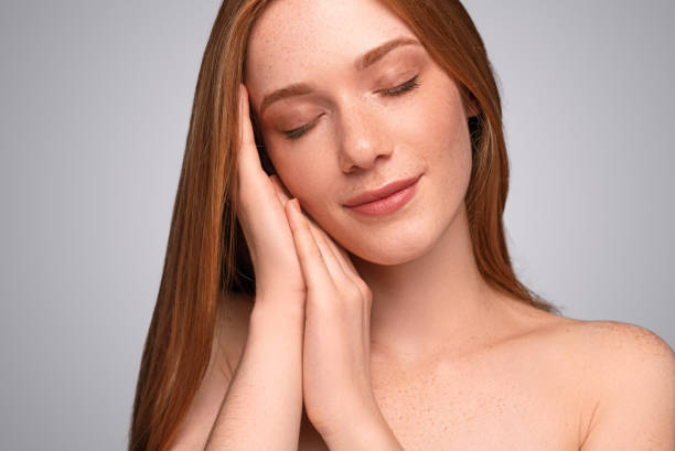 istock Freckled woman clasping hands near cheek 1279895875