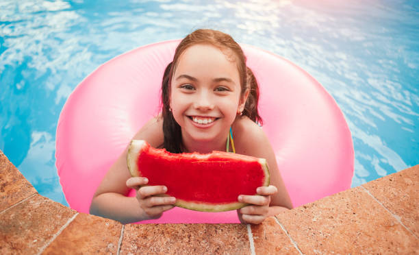 petite fille joyeuse avec la pastèque dans la piscine - swimming pool child swimming buoy photos et images de collection