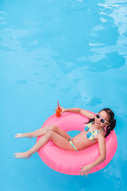 istock Cheerful girl with fruit drink chilling on inflatable ring in pool 1279895931