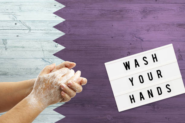 istock Qatar flag background on wooden surface. Minimal wash your hands board with minimal international hygiene concept hand detail. 1279896421