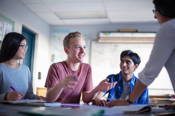 istock Smiling student asking teacher in diverse multi-cultural classroom 1279897598