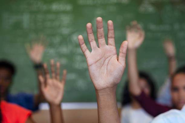istock Diverse multi-cultural teenagers with hands raised sitting in classroom 1279901648