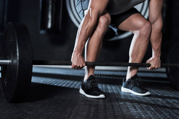 Shot of an unrecognisable man lifting a barbell during his workout at a gym