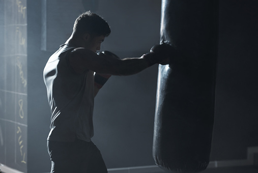 Shot of a young man practicing his boxing routine at a gym