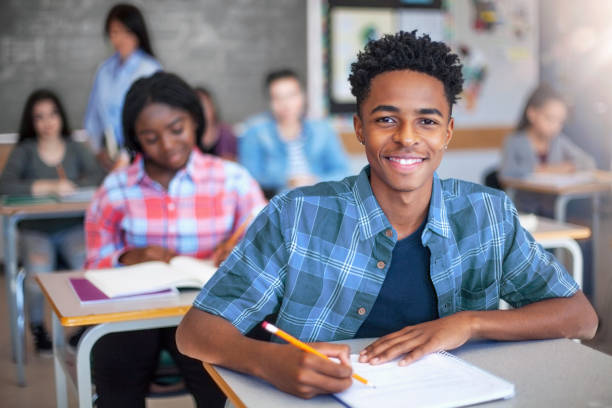 istock Portrait of smiling Black ethnicity student writing in classroom 1279902636